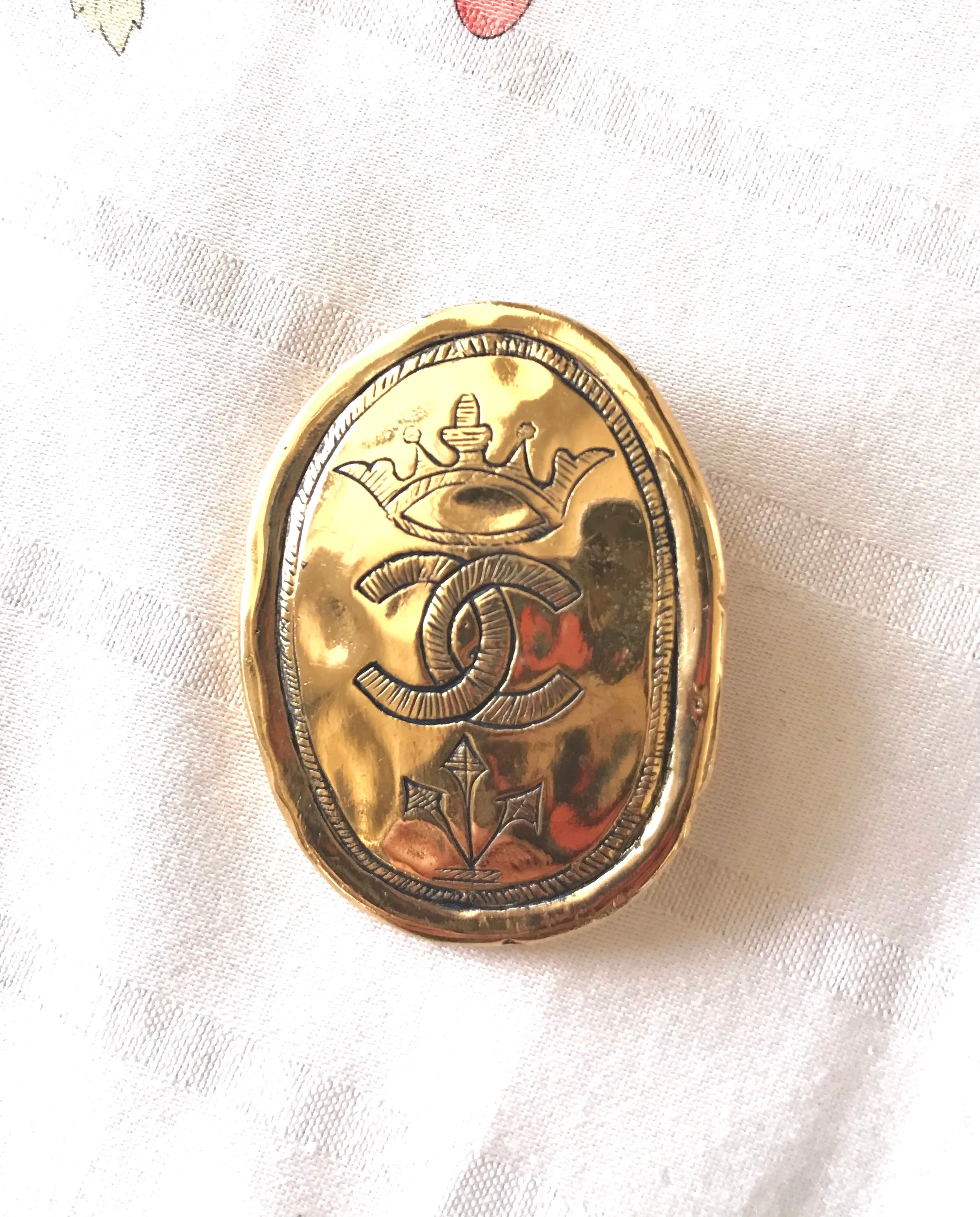 Vintage CHANEL gold tone large brooch in oval coin shape with CC logo and crown embossed motif. Rare masterpiece jewelry. 060620re3