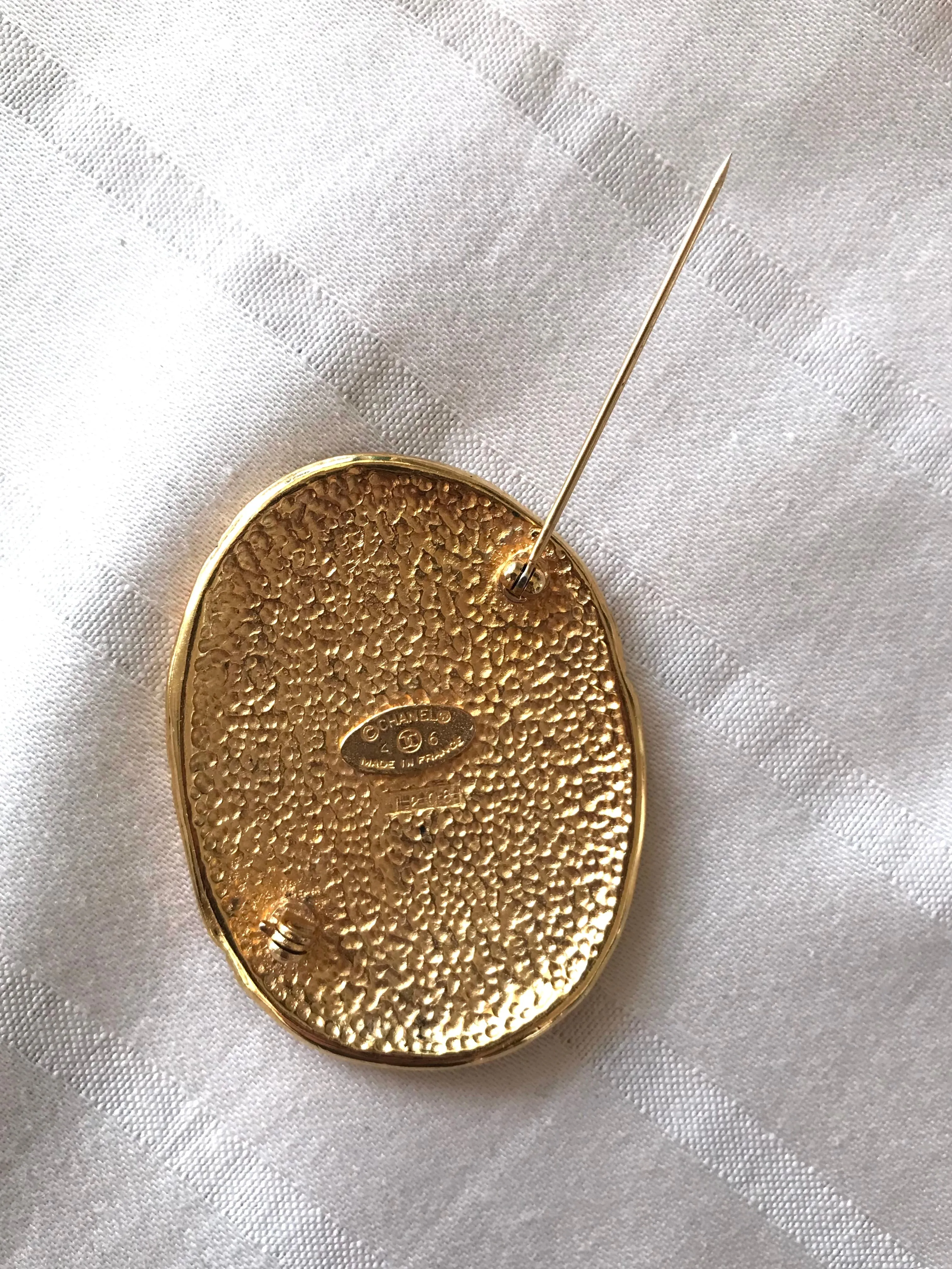 Vintage CHANEL gold tone large brooch in oval coin shape with CC logo and crown embossed motif. Rare masterpiece jewelry. 060620re3